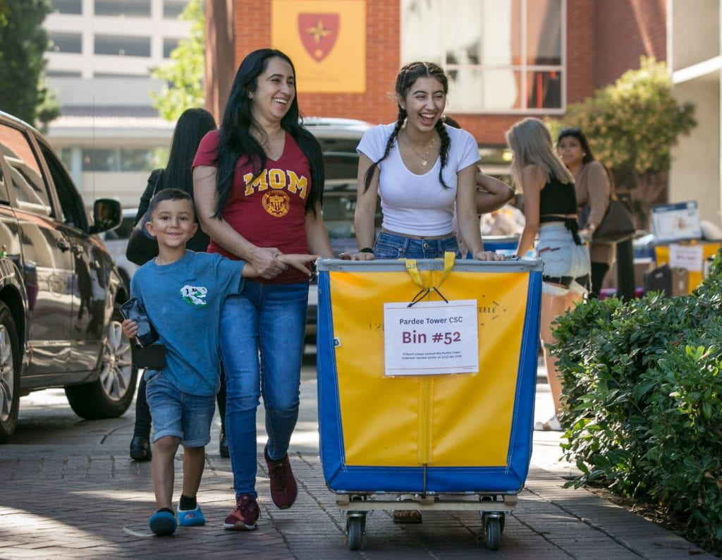 Photo of a student and her mother and younger brother moving into on campus housing