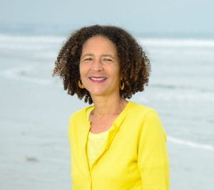 Photo of Dr. Alison Rose Jefferson in a yellow suit on the beach.