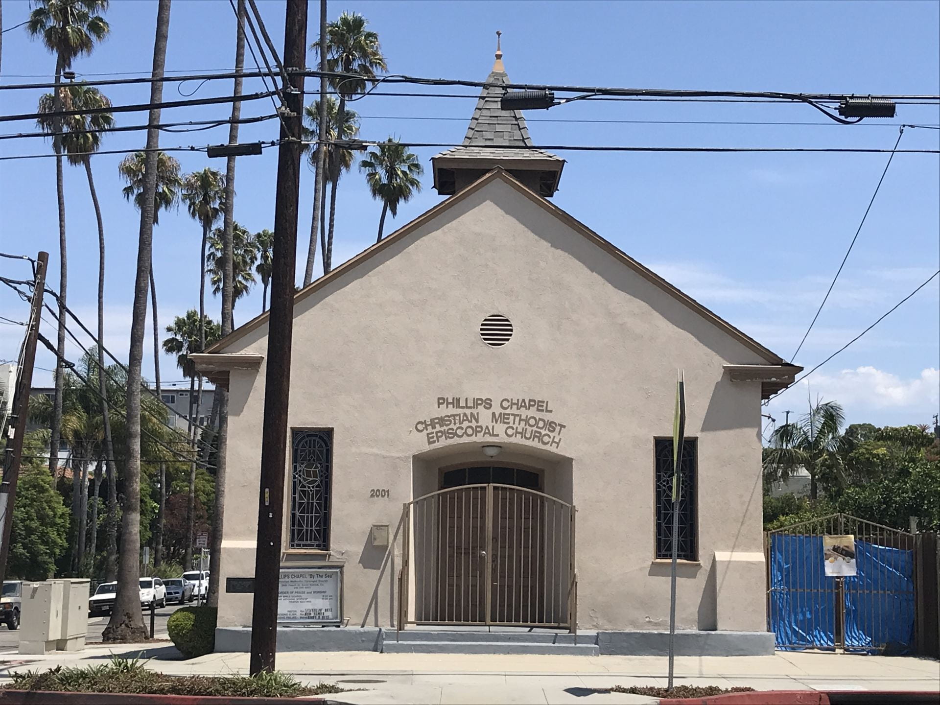 A light-brown church with palm trees behind.