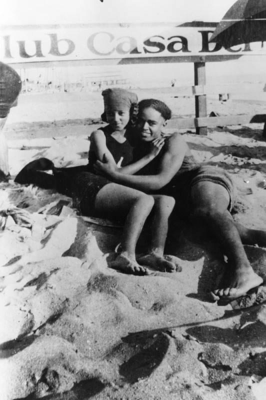 A young couple hugging in the sand on the beach, 1924.