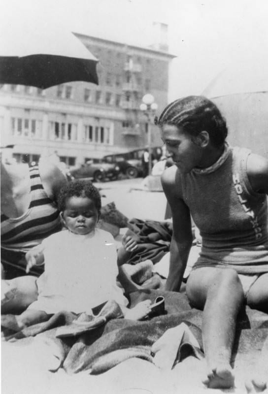 A baby and a young woman on the beach in 1931.