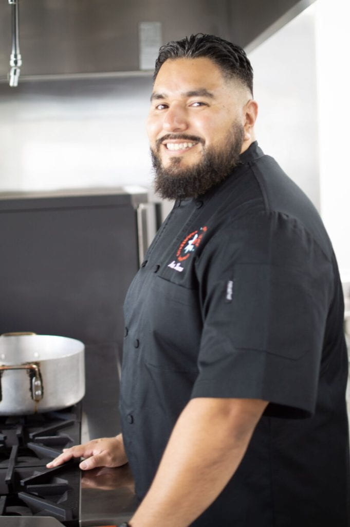Chef Art Luna, smiling next to a stove.