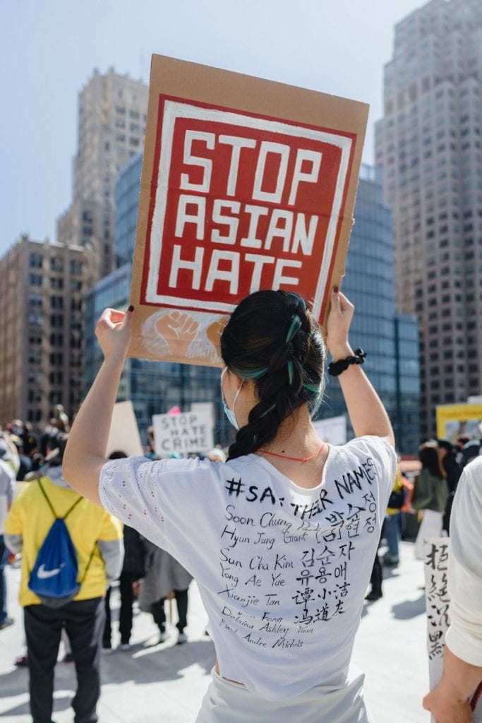 Image of Woman with braid at a protest holding a sign that says stop asian hate.